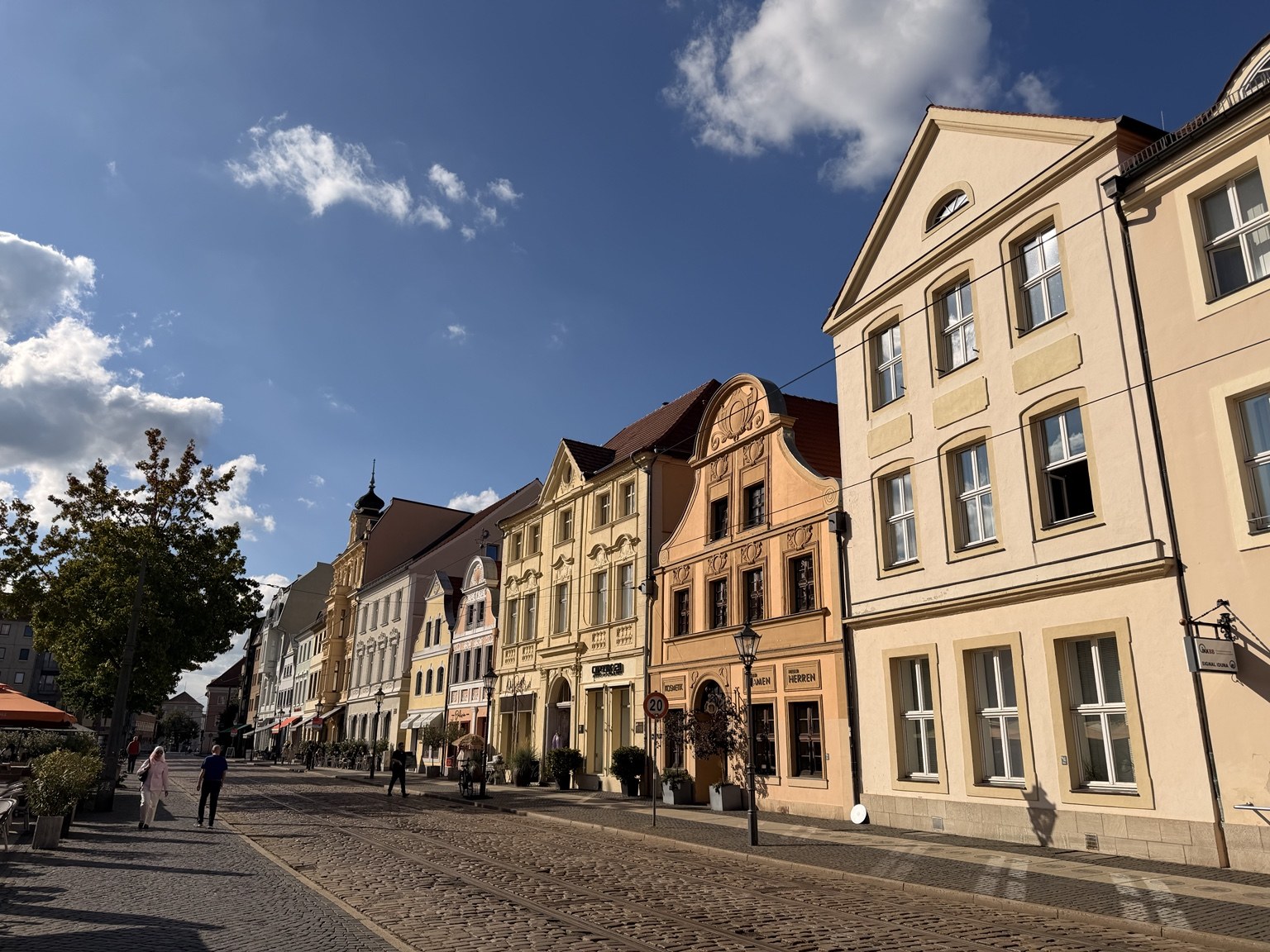 Renovierte Häuser am Altmarkt in Cottbus unter blauem Himmel, mit Menschen auf dem Platz.