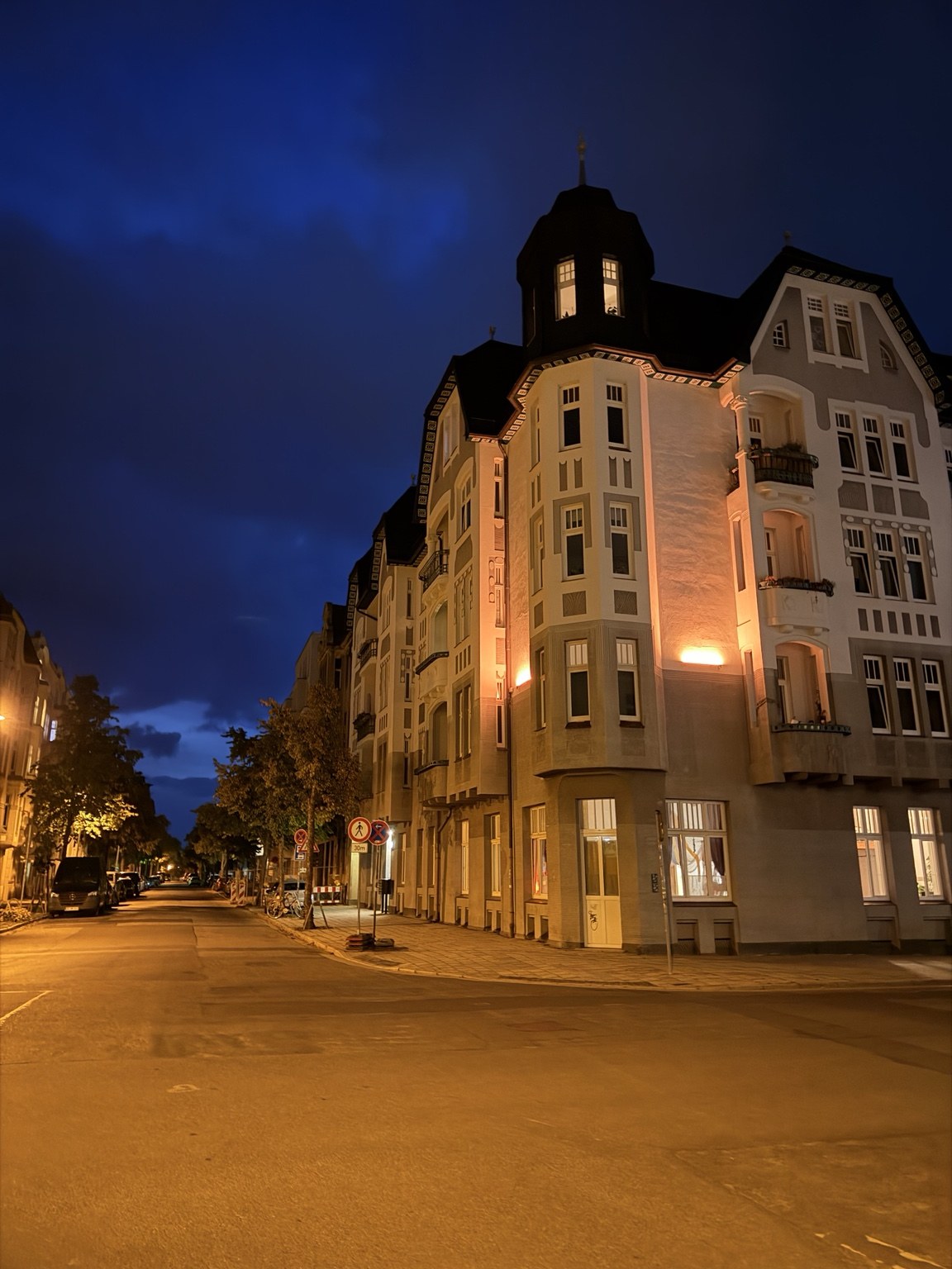 Leere Straße in Cottbus am Sonntagabend, beleuchteter Altbau mit Erker und Turm.