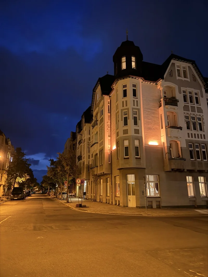 Leere Straße in Cottbus am Sonntagabend, beleuchteter Altbau mit Erker und Turm.